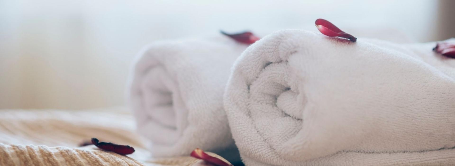 Camera semplice con letto matrimoniale, lenzuola bianche e copriletto grigio.