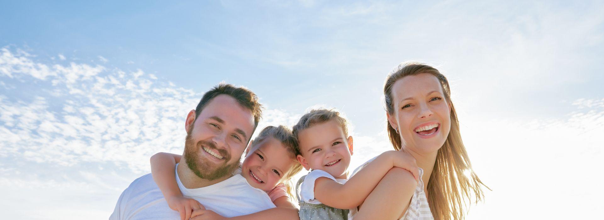 Famiglia felice in posa all'aperto sotto un cielo azzurro.