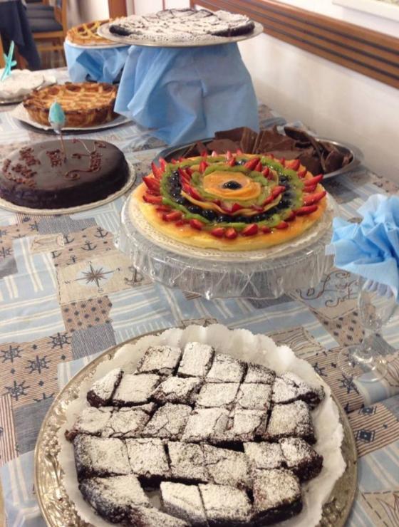 Varietà di dolci su un tavolo, inclusa una crostata di frutta e torte al cioccolato.