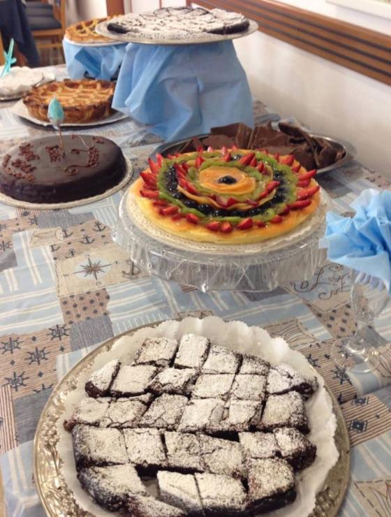 Tavola imbandita con dolci vari, tra cui torte alla frutta e al cioccolato.