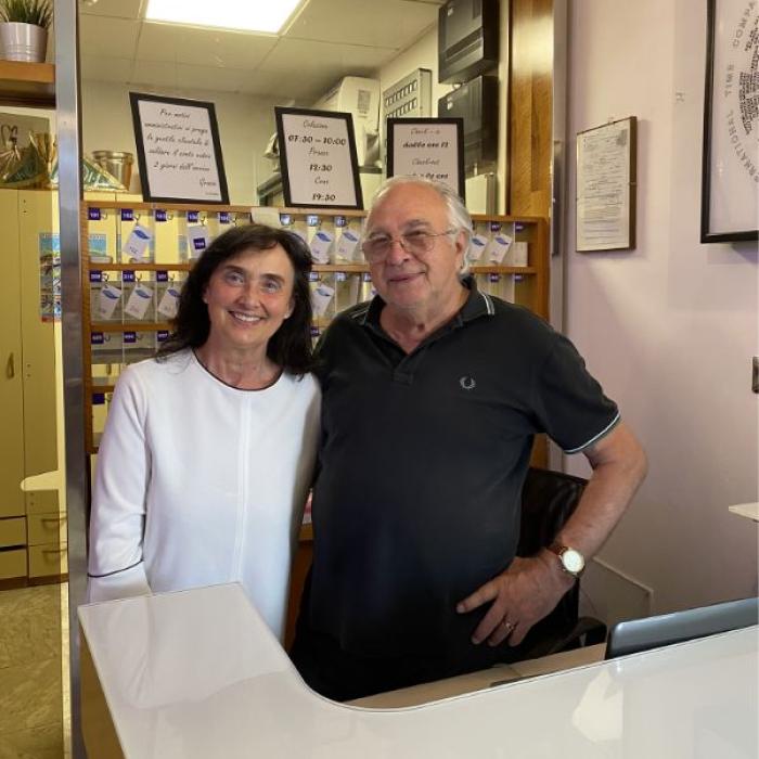 Due persone sorridenti dietro un bancone in una reception.