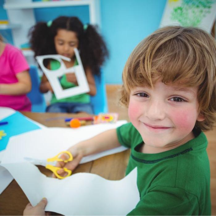 Bambini che fanno attività artistiche con carta e forbici in classe.