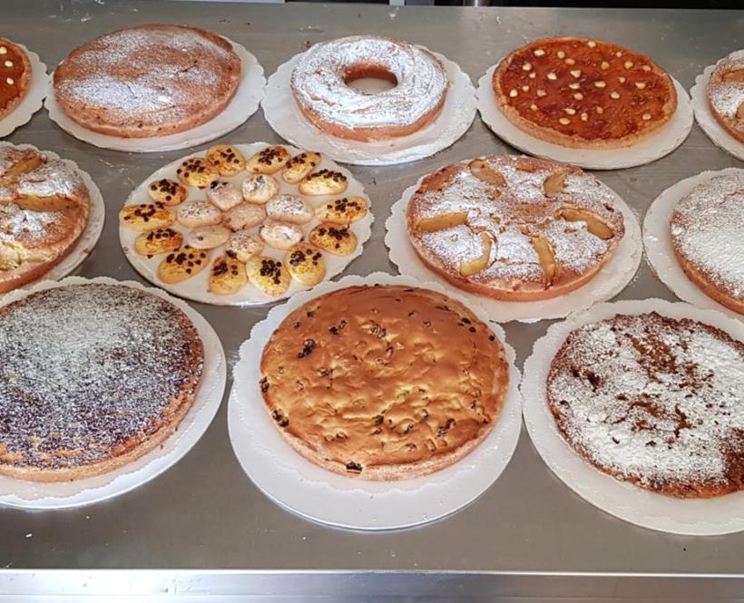 Varietà di torte e dolci su un tavolo, decorati con zucchero a velo e frutta.