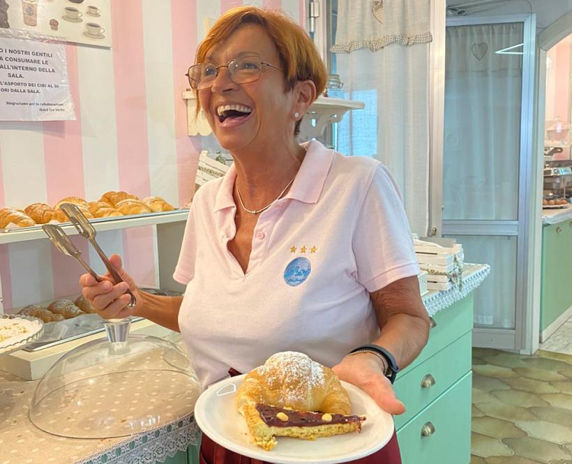 Donna sorridente serve un dolce in una pasticceria accogliente.